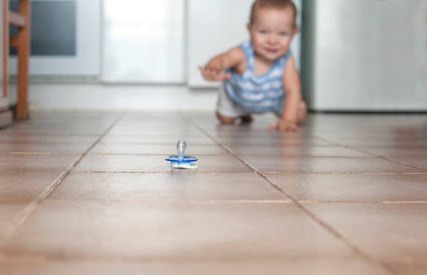 Baby crawling toward pacifier on the floor. Baby safe floor cleaners.